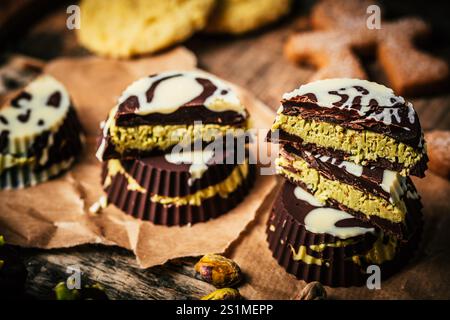 Praline alla moda fatte in casa al cioccolato di Dubai, cioccolato ripieno di crema di pistacchio croccante, su sfondo in legno Foto Stock