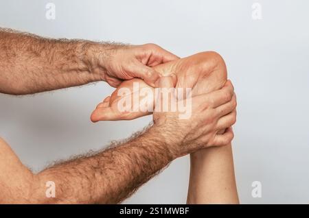 Pressione delle dita sul piede, riflessologia. Donna che riceve un massaggio ai piedi. Centro benessere, sfondo grigio Foto Stock