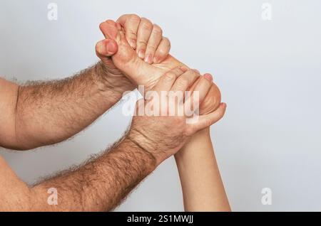 Dettaglio della pressione delle dita sul piede, riflessologia. Donna che riceve un massaggio ai piedi. Centro benessere, sfondo grigio Foto Stock