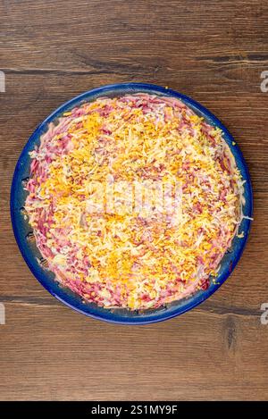 Vista dall'alto di un piatto blu pieno di aringhe sotto un'insalata di pelliccia. Cucina casalinga. Foto Stock