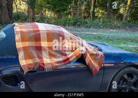 Auto coperta da una coperta colorata per evitare la formazione di ghiaccio durante la notte sul parabrezza anteriore e sul finestrino del conducente, Regno Unito Foto Stock