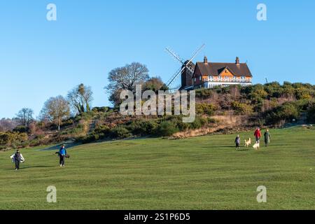 Golfisti e camminatori al Reigate Heath Windmill vicino al circolo del Reigate Heath Golf Club, Surrey Inghilterra, Regno Unito, in una giornata invernale soleggiata con cielo blu Foto Stock