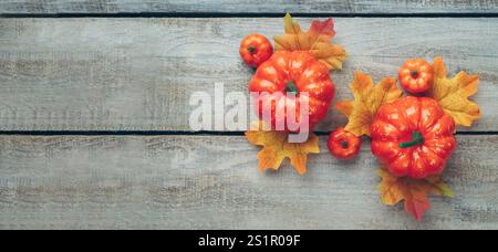 Decorazione del Ringraziamento e dell'autunno realizzata con foglie autunnali e zucca su sfondo chiaro in legno. Disposizione piatta, vista dall'alto con spazio di copia. Foto Stock