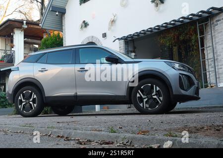 Bucarest, Romania – 1 gennaio 2025: Vista laterale della Peugeot 2008 ibrida argentata parcheggiata di fronte alla casa Foto Stock