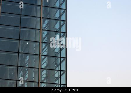 L'edificio degli uffici si erge alto contro un cielo azzurro, riflettendo l'architettura moderna e il progresso urbano. Foto Stock