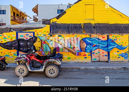 Colorato murale Street Art su un edificio giallo con quad in primo piano, Isla Holbox, Messico Foto Stock