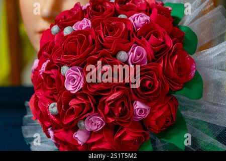 Uno splendido bouquet presenta rose rosse e rosa vivaci, impreziosite da dettagli argentati. Perfetto per matrimoni o eventi speciali, questo spettacolo organizzato Foto Stock