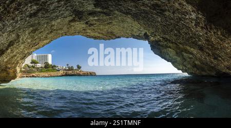 Cattura una vista mozzafiato delle acque turchesi e di un resort a cala domingos, maiorca, dall'interno di una grotta lungo la costa Foto Stock