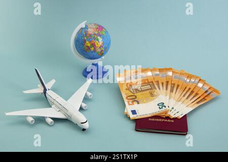 Concetto di vacanza estiva con barca giocattolo, aereo, globo e cinquanta banconote da euro su sfondo blu Foto Stock