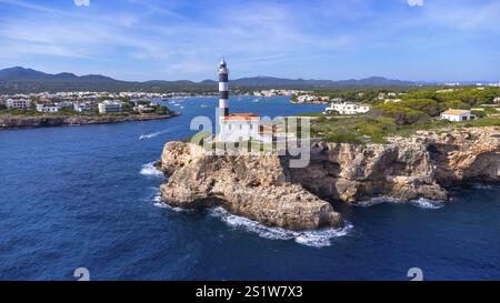 Vista aerea del faro di portocolom a maiorca, spagna, in piedi su una scogliera che si affaccia sul mar mediterraneo in una soleggiata giornata estiva Foto Stock