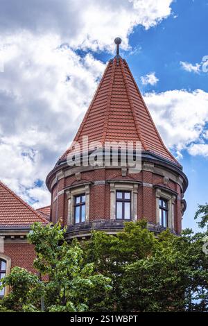 Interessante facciata di case di Berlino con mattoni, torre rotonda e vecchie finestre. Casa in pietra con vecchie finestre e torre rotonda a Berlino Foto Stock