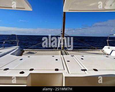 L'elegante prua di un catamarano che taglia le acque aperte dell'Oceano Atlantico, mostrando un tranquillo viaggio marittimo. Foto Stock