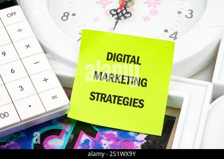Concetto di business. Parole STRATEGIE DI MARKETING DIGITALE scritte su un adesivo verde chiaro. Foto Stock