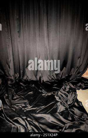 Tessuto nero lucido o tenda avvolto su pareti e pavimento in uno studio fotografico o a casa, che funge da sfondo. Foto Stock