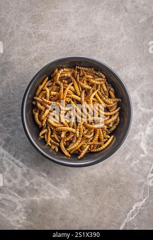 Vermi salati secchi. Vermi arrostiti nel recipiente su un tavolo da cucina. Foto Stock