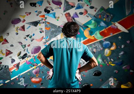 Atleta sportivo, arrampicatore in piedi contro un muro ripido in palestra all'interno. Sport estremi e Boulder Concept Foto Stock
