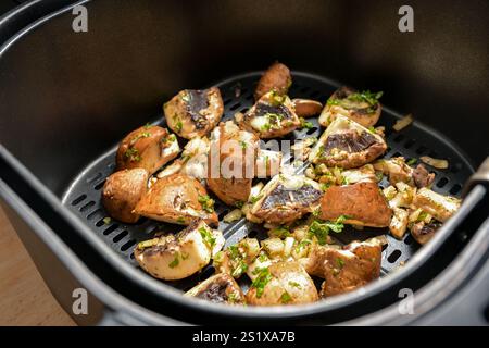 I funghi con erbe, spezie e un po' di olio vengono cotti in una friggitrice ad aria calda, un metodo salutare di cottura delle verdure, una messa a fuoco selezionata, una profondità ridotta del fiel Foto Stock