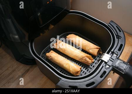 Rotoli croccanti di pasta filla ripiena o involtini primavera in una friggitrice ad aria calda, cottura sana con basso contenuto di grassi, spazio per copiare, messa a fuoco selezionata, profondità ridotta di f Foto Stock
