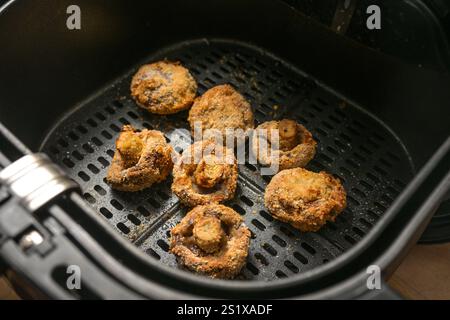 Alcuni funghi impanati in una friggitrice ad aria calda, cotti al forno croccanti all'esterno, succosi all'interno, finger food fatti in casa con verdure a basso contenuto di grassi Foto Stock