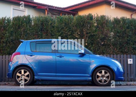 Bucarest, Romania – 4 gennaio 2025: Vista laterale della Suzuki Swift Blue car parcheggiata di fronte alla casa Foto Stock