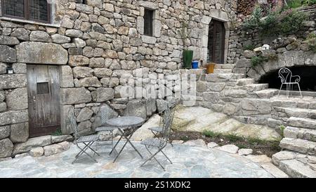 Tavolo bistrot e sedie seduti su un patio in pietra fuori da una casa europea in muratura a secco , cevennes; lozere, francia Foto Stock