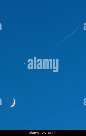 Un aereo che sembra volare oltre la recente congiunzione di Venere e Luna in un cielo sereno il 3 gennaio 2025 (Regno Unito) Foto Stock