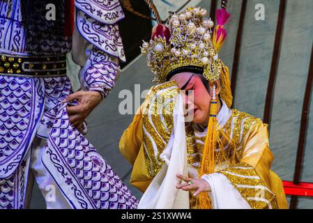 Artisti d'opera cinesi tradizionali che mostrano intricati costumi ed espressioni drammatiche durante le celebrazioni del capodanno cinese nel quartiere cinese di Chinatow di Bangkok Foto Stock