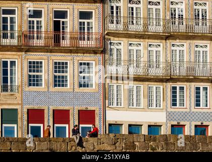 Porto, Portogallo, 25 dicembre 2024: Conversazioni illuminate dal sole sulle facciate storiche di Ribeira Foto Stock