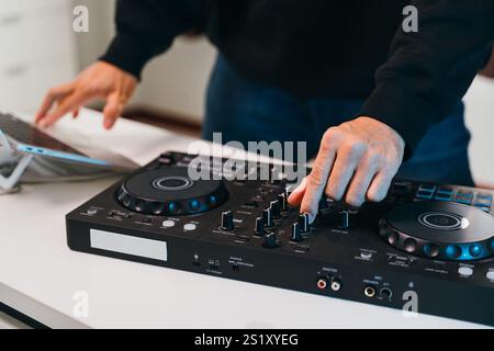 Primi piani di un DJ che mescola perfettamente brani su una console mixer minimalista in un elegante evento domestico. Foto Stock