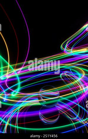 Una luce colorata si diffonde in una fotografia a lunga esposizione intorno a una sfera di vetro su uno specchio. Riflessi e vortici di sfondo luminoso Foto Stock