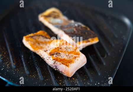 Nella padella nera quadrata sono presenti due pezzi di bistecche di salmone alla griglia Foto Stock