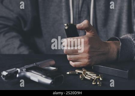 Uomo che carica mgazina di pistola semiautomatica a casa Foto Stock