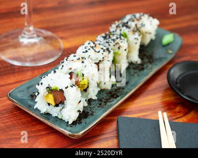 Set di panini sushi freschi con salmone, avocado e semi di sesamo serviti sul piatto. Foto Stock