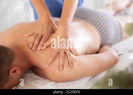 La massaggiatrice femminile si occupa di problemi alle spalle per i clienti di atleta maschile. Primo piano Foto Stock