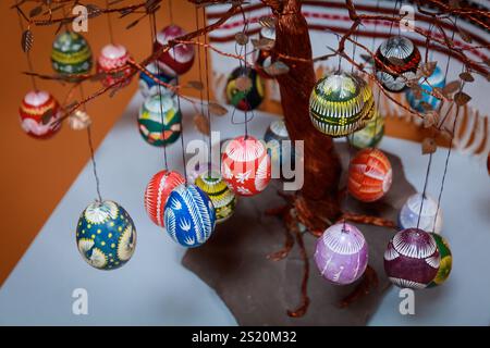 Un albero con molte uova colorate appese ad esso. Le uova sono di diverse dimensioni e colori, e sono appese ai rami dell'albero. La sc Foto Stock