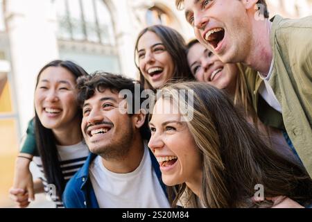 Gruppo felice di giovani studenti che si abbracciano a vicenda ridendo all'aperto. Foto Stock