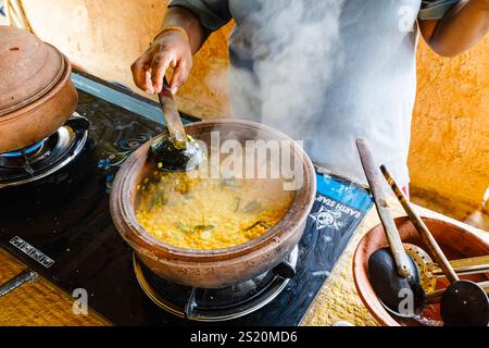 Preparazione di una ciotola di deliziose lenticchie fumanti cucinate su un piano cottura a gas ad anello a Wakwella, distretto di Horagampita, vicino a Galle, Sri Lanka Foto Stock