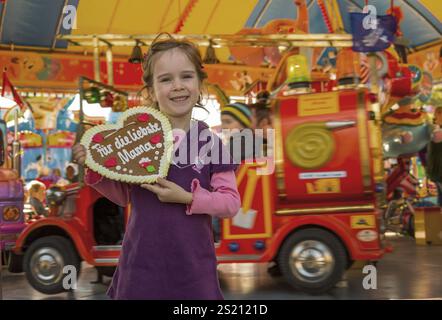 Un bambino ha un cuore fatto di pan di zenzero. Iscrizione: Per la cara mamma. Foto simbolica per la festa della mamma in Austria Foto Stock