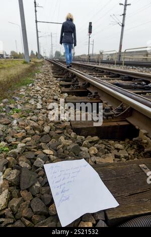 Una giovane donna lascia una lettera di addio e cammina su un binario ferroviario con l'intenzione di suicidarsi. Lettera in inglese Foto Stock