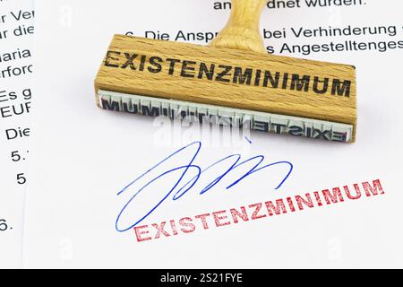 Un timbro di legno giace su un documento. Iscrizione: Existenzminimum Austria Foto Stock