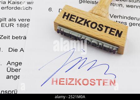 Un timbro di legno giace su un documento. Iscrizione tedesca: Costi di riscaldamento Austria Foto Stock