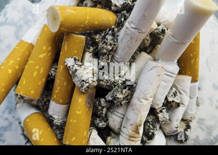 Mozziconi di sigaretta in un posacenere, foto simbolica per il fumo a catena e pericolo per la salute Austria Foto Stock