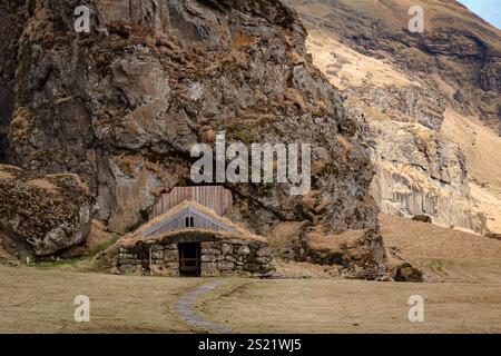 Piccola casa di pietra costruita in una montagna. Foto scattata durante una giornata invernale nel sud dell'Islanda Foto Stock