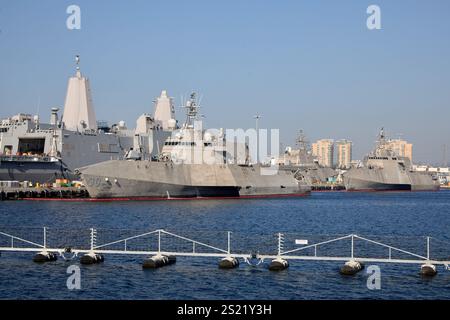 San Diego, California, Stati Uniti. 21 dicembre 2024. Una vista della USS Canberra (LCS-30), una nave da combattimento Littoral classe Independence, insieme ad altre navi della base navale di San Diego. Dietro di essa, la più grande struttura di una nave del porto di trasporto anfibio si erge alta, mostrando la variegata flotta della Marina degli Stati Uniti per le operazioni costiere e anfibie. Il design elegante dell'LCS contrasta con la forma robusta della banchina di trasporto, sottolineando il loro ruolo specializzato nella moderna strategia navale. (Credit Image: © Ian L. Sitren/ZUMA Press Wire) SOLO PER USO EDITORIALE! Non per USO commerciale! Foto Stock