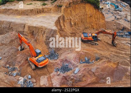 Gli escavatori scavano il terreno nella fossa di fondazione di un edificio in un cantiere Foto Stock