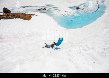 Un uomo sta in piedi su un dormitorio per scivolare giù da una collina verso un lago ghiacciato Foto Stock