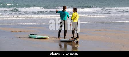 Un'immagine panoramica di un istruttore di surf della Escape Surfing School che tiene una lezione di surf uno a uno con un principiante a Towan Beach a Newquay Foto Stock