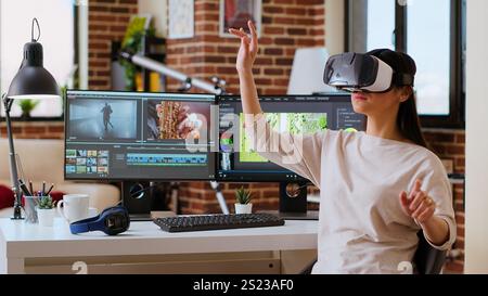 La creatrice di video donna asiatica utilizza un visore per la realtà virtuale alla sua scrivania, strumenti tecnologici moderni per la sua occupazione creativa. Artista femminile che modifica e mixa video clip per progetti cinematografici. Telecamera B.. Foto Stock