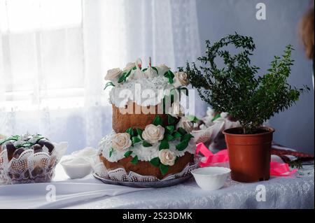 Elegante torta a due livelli adornata con rose di panna su un tavolo. Foto Stock