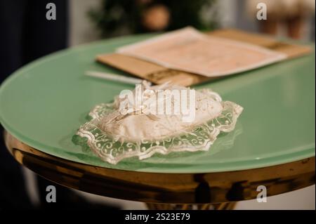 Elegante cuscino decorativo bianco con finiture in pizzo su un tavolo verde. Foto Stock